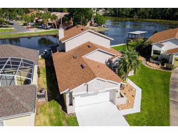 An aerial view of a waterfront home with a well-manicured lawn and lake access at 830 Palm Harbor Ct, Leesburg, FL 34748