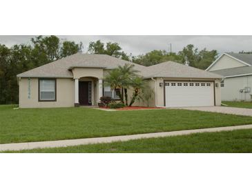 Charming single-story home featuring a well-manicured lawn and a two-car garage at 13546 Biscayne Grove Ln, Grand Island, FL 32735