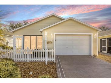 Charming single-story home with a well-manicured lawn, white picket fence, and attached garage at 2036 Chesapeake Pl, The Villages, FL 32162