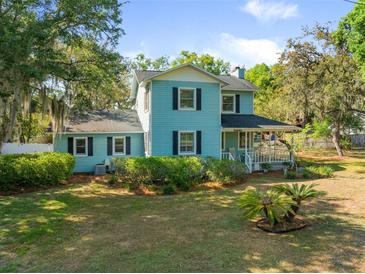 Charming two-story home with a front porch, lush landscaping, and mature trees in a desirable neighborhood at 25541 Troon Ave, Sorrento, FL 32776