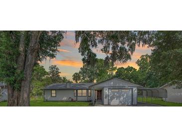 Charming single story home featuring a gray exterior, mature landscaping, and carport at 5011 Se 33Rd Ave, Ocala, FL 34480