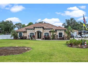 Stunning single-story home featuring a tile roof, well-manicured lawn, and lush landscaping at 16200 E Shirley Shores Rd, Tavares, FL 32778