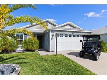 A well-maintained single-story home featuring a two-car garage and an adjacent golf cart at 1633 Manserra St, The Villages, FL 32163