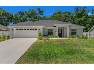 Charming single-story home features a manicured lawn, two car garage, and inviting front porch columns at 16380 Se 84Th Ct, Summerfield, FL 34491