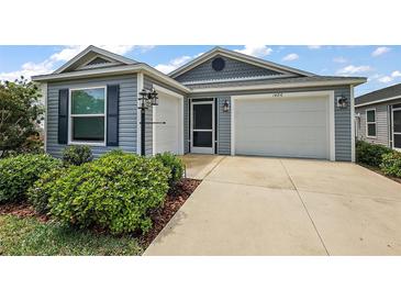 Charming single-Gathering home showcasing a two-car garage, manicured landscaping, and a welcoming entrance at 1486 Joshua Ct, The Villages, FL 32163