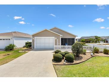 Charming home featuring a garage, screen room, white picket fence, and well-manicured landscaping at 1486 Olympia St, The Villages, FL 32163