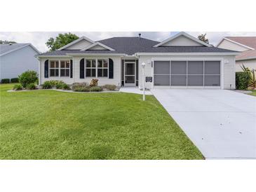 Charming single-story home featuring a well-manicured lawn, screened garage, and inviting front entrance at 17036 Se 79Th Clearview Ave, The Villages, FL 32162