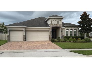 Charming single-story home featuring a three-car garage, brick driveway, and well-maintained landscaping at 2504 Cavender Creek Rd, Minneola, FL 34715