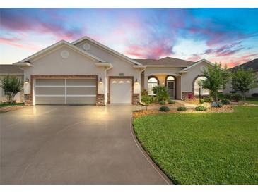Charming single-story home featuring a well-manicured lawn, beautiful landscaping, and a spacious driveway at 10977 Se 169Th Ln, Summerfield, FL 34491