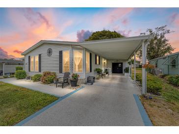 Well-maintained single-story home with a covered carport, beautiful landscaping, and charming curb appeal at 1109 Paradise Dr, The Villages, FL 32159
