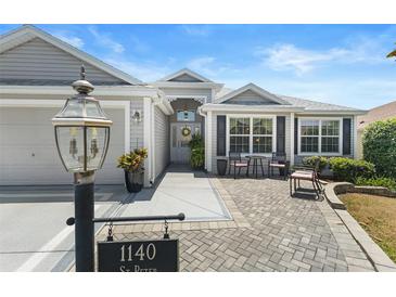 Charming single-story home featuring a cozy front patio and lush landscaping at 1140 Eureka Mill Run, The Villages, FL 32162