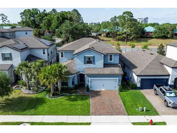 Two-story home with a brick driveway, lawn, and tropical landscaping featuring palm trees at 1268 Patterson Ter, Lake Mary, FL 32746