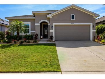 Charming home with a two-car garage, well manicured landscaping and green lawn at 13304 Magnolia Valley Dr, Clermont, FL 34711