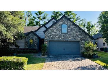 Charming exterior view of a stone-accented home with a paved driveway and well-manicured landscaping at 1893 Banning Beach Rd, Tavares, FL 32778