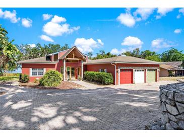 Charming one-story home featuring a circular driveway, three-car garage, and picturesque landscaping at 2400 N Griffin Dr, Leesburg, FL 34748