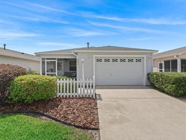 Charming single-story home featuring a white picket fence, and a two-car garage at 2450 Kingstree Pl, The Villages, FL 32162