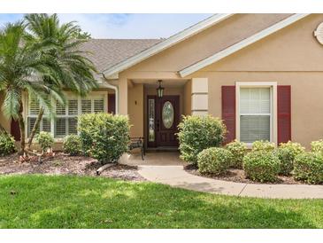 Charming home entrance featuring a beautifully landscaped yard and stylish front door with an oval glass window at 7685 Lake Angelina Dr, Mount Dora, FL 32757