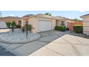 Beige single-Gathering home with a two-car garage, white rock landscape, and a concrete driveway in a sunny, pleasant neighborhood at 919 Medira Dr, The Villages, FL 32159