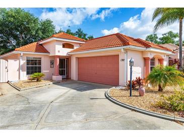 Charming single-story home featuring a red tile roof, two-car garage, and meticulously landscaped front yard at 1305 Santa Maria Ave, The Villages, FL 32159