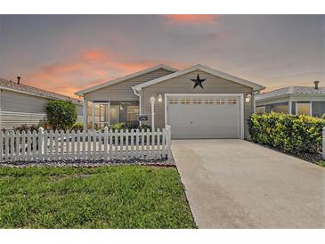 Charming single story home with well-manicured lawn, picket fence, and inviting curb appeal at 2296 Whisper St, The Villages, FL 32162