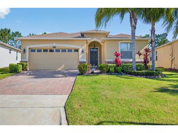 Charming single-story home with a brick driveway, lush lawn, and tropical landscaping at 3948 Serena Ln, Clermont, FL 34711