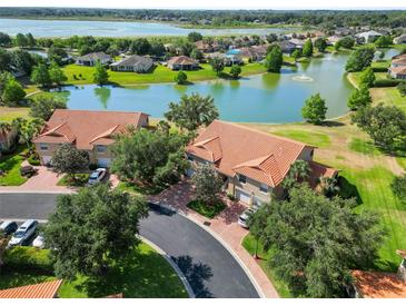 Stunning aerial view of townhomes with terracotta roofs overlooking a tranquil lake and lush green landscape at 5492 Compass Pt, Oxford, FL 34484