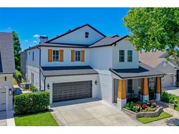 Beautiful two-story home with a dark gray garage door, wood-accented porch columns, and manicured landscaping at 722 Barefoot Bay Loop, Clermont, FL 34736