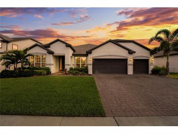 Beautiful home featuring a well-manicured lawn, brick driveway, and a two-car garage under a colorful, picturesque sunset at 743 Brooks Field Drive Dr, Winter Garden, FL 34787