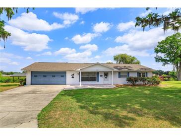 Charming single-story home with a lush green lawn, blue shutters and a matching blue garage door at 1110 Fairfax St, Leesburg, FL 34748
