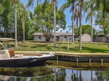 Waterfront home featuring a private dock, lush landscaping, and direct access to the canal at 11114 Lake Eustis Dr, Leesburg, FL 34788