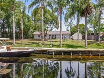 Waterfront backyard featuring a wooden dock, lush landscaping, and a view of the canal at 11114 Lake Eustis Dr, Leesburg, FL 34788