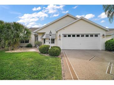 Charming single-story home with a well-manicured lawn, palm trees, and a two-car garage at 1318 Guerra Ave, The Villages, FL 32159