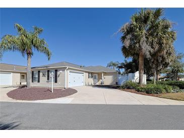 Charming single-story home features an attached garage, a well-manicured lawn, and beautiful palm trees at 1451 Rosedale Way, The Villages, FL 32162