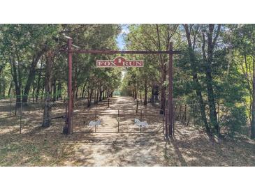 Gated entrance to Fox Run, leading to a tree-lined drive at 27011 Se Highway 42, Umatilla, FL 32784