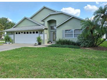 Charming single-story home featuring a lush front lawn, manicured landscaping, and an attached two-car garage at 2750 Coral Reef Way, Tavares, FL 32778
