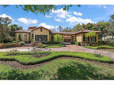 Beautiful front exterior of home with red tile roof, manicured landscaping and brick paved driveway at 32543 Hawks Lake Ln, Sorrento, FL 32776