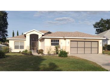 Charming single-story home boasts a well-manicured lawn and an inviting screened entryway and two-car garage at 5075 China Sea Dr, Tavares, FL 32778