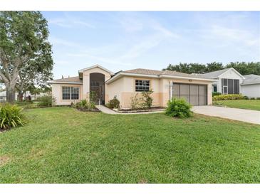 Charming single-story home featuring a well-manicured lawn, and a screened front entryway at 5075 China Sea Dr, Tavares, FL 32778