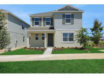 Charming two-story home with light exterior, manicured lawn, and dark shutters on a sunny day at 5105 Blanket Flower St, Apopka, FL 32712