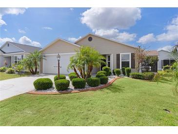 Charming home with lush green lawn, manicured landscaping, and palm trees for a tropical feel at 744 Shelton St, The Villages, FL 32163