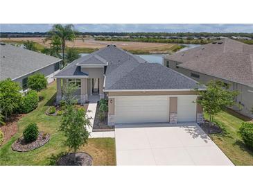 Inviting exterior of a home boasting a 2-car garage, a well-maintained lawn, and picturesque landscaping at 8664 Bridgeport Bay Cir, Mount Dora, FL 32757