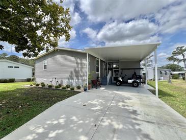 Charming single-story home with gray siding, well-maintained landscaping, and a covered carport perfect for a golf cart at 102 Dogwood Trl, Leesburg, FL 34748