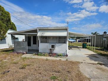 Modest single-story home with covered parking and small porch under a blue sky at 1425 County Dr, Tavares, FL 32778
