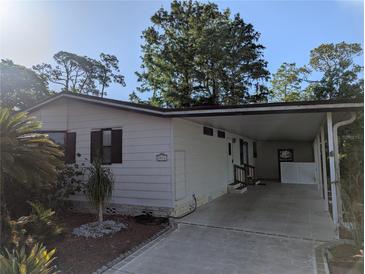 Charming home features a covered carport, a manicured garden, and a clean exterior design at 2871 Myakka River Rd, Tavares, FL 32778