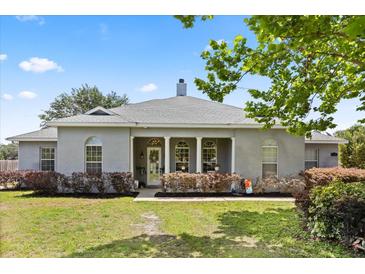 Charming single story home featuring a neutral exterior, arched windows and manicured landscaping on a lush lawn at 28924 Discovery Rd, Tavares, FL 32778