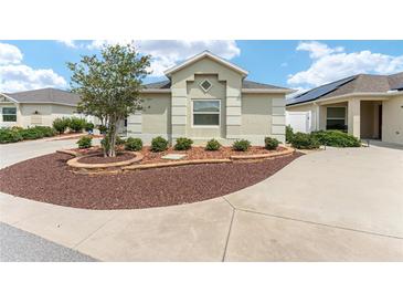 Landscaped front yard with a charming stone accent garden and lush greenery, with concrete driveways at 9181 Se 166Th Sprung Ln, The Villages, FL 32162