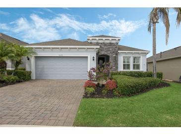 Charming single-story home featuring a stone accent wall, paver driveway, and well-manicured landscaping at 1027 Timbervale Trl, Clermont, FL 34715