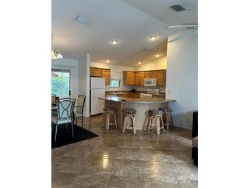 Open kitchen with a large island and seating, plus wood cabinets at 1060 Davenport Dr, The Villages, FL 32162