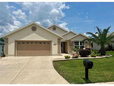 Charming single-story home featuring a manicured lawn, well-maintained landscaping, and a two-car garage at 11277 Se 170Th Ln, Summerfield, FL 34491