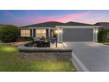 Charming home featuring a landscaped yard, patio, and attached two-car garage at 1309 Piney Woods Path, The Villages, FL 32163